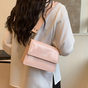 Pink patent leather crossbody bag with wide strap and silver studs shown on a model