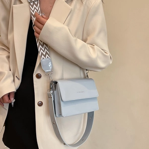 Glossy patent leather small square crossbody bag with dual straps shown on a model