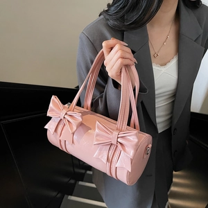 Pink glossy patent leather barrel bag with oversized bows for stylish shoulder and crossbody wear