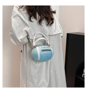 Model wearing a light blue rugby-shaped crossbody bag with chain strap and white handles
