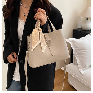 Détail du sac seau en cuir beige avec foulard à motifs cœurs et boucle métallique