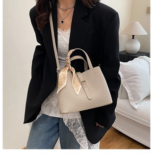 Vue détaillée du sac seau beige en cuir grainé avec foulard en soie à motif cœurs