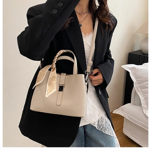 Détail du sac seau beige avec texture grainée et foulard décoratif à motif de cœurs