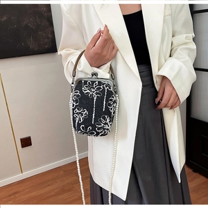 Détail d'un sac brodé style chinois avec chaîne en perles et fermoir sur un mannequin