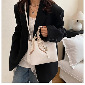 Détail du sac seau blanc avec texture litchi et foulard à cœurs sur la poignée