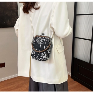 Détail de la broderie florale sur le sac bandoulière noir avec bandoulière perle
