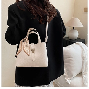 Détail du sac seau crème en cuir grainé avec foulard en soie à motif cœur sur la poignée