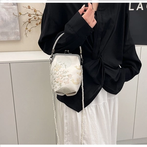 Détails des broderies florales et de la poignée en cristal d'un sac à fermoir vintage