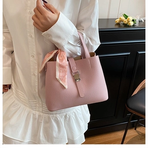 Détail du sac seau rose en cuir grainé avec foulard en soie et boucle métallique robuste