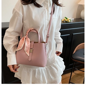 Détail du sac seau rose avec poignée en soie et breloque cœur sur robe blanche