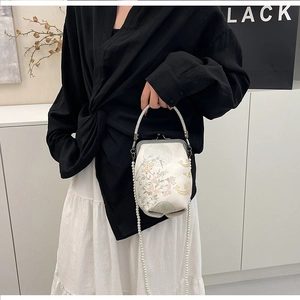 Détail du sac brodé avec bandoulière en perles et poignée en strass étincelants