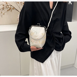 Gros plan sur la broderie vintage aux motifs floraux et bandoulière en perles du sac blanc