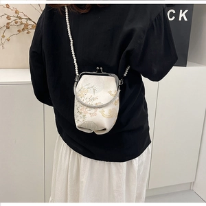 Détail du sac bandoulière en soie brodée avec motifs floraux et chaîne en perles