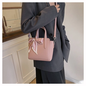 Sac seau en cuir rose avec foulard décoratif à cœurs porté par un mannequin