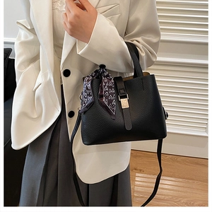 Détail du sac seau noir avec texture litchi, foulard décoratif et boucle en métal argenté