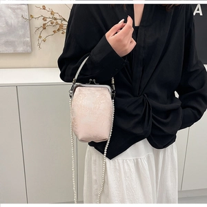 Détail du sac brodé rose avec chaîne en perles et texture en soie porté par un mannequin