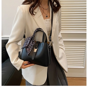 Détail du sac seau noir grainé avec foulard en soie à motif cœur enroulé sur l'anse