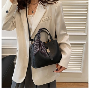 Détail du sac seau noir en cuir grainé avec foulard décoratif et fermoir métallique