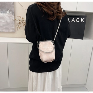 Petit sac bandoulière en jacquard rose avec chaîne en perles porté par un mannequin
