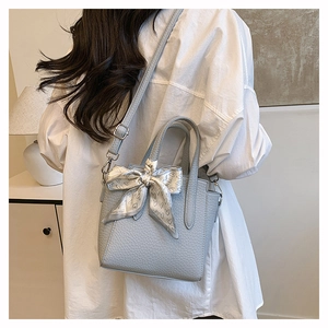 Détail du sac seau en cuir bleu clair avec foulard décoratif en soie à imprimé cœur