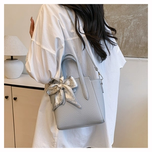 Gros plan d'un sac seau bleu clair avec motif litchi et foulard en soie à cœurs
