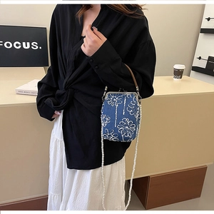 Détail de la broderie florale sur sac en denim avec une élégante bandoulière en perles