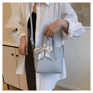 Détail du sac seau bleu clair avec texture litchi et foulard en soie à imprimé cœur