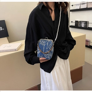 Détail du sac en jean brodé avec bandoulière en perles et fermoir métallique sur modèle