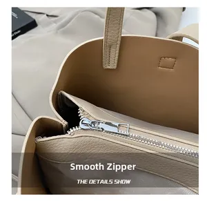 Gros plan sur la fermeture éclair en métal et le cuir grainé du sac seau beige