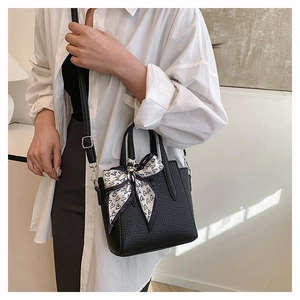 Détail du sac à main noir texture galet avec foulard à motifs cœurs sur l'anse