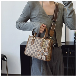 Detailed shot of retro monogram tote bag with wide jacquard strap and leather flower charm