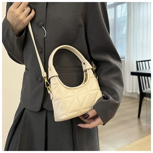 Detail of cream quilted handbag featuring geometric triangle stitching and gold hardware