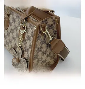 Close-up of vintage brown printed tote bag with leather trim and gold metal hardware