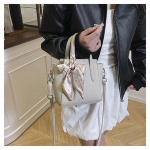 Détail du sac seau beige à motif litchi avec foulard en soie et bandoulière amovible