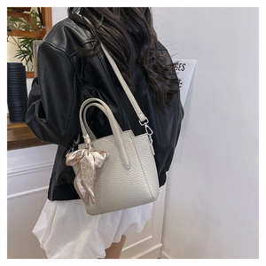 Détail du sac seau en cuir crème avec un foulard décoratif en soie à cœurs