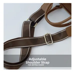 Detail of adjustable brown nylon shoulder strap with gold metal buckle on tote bag
