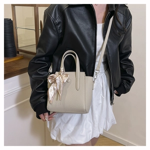 Mini sac seau beige avec foulard en soie porté par un mannequin en décor minimaliste