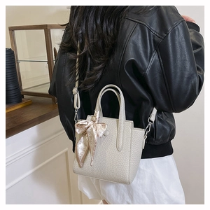Détail du sac à bandoulière en cuir crème texturé avec foulard en soie floral décoratif