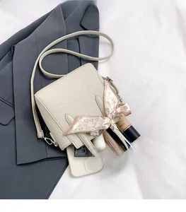 Détail du grand espace de rangement dans un sac beige en cuir avec foulard