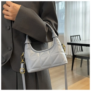Detail of light blue quilted hobo bag with white stitching and gold hardware on blazer