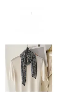Detail of pleated skinny scarf with black and white wavy pattern on a white knit sweater