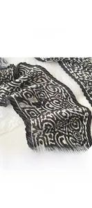 Detail of pleated silk scarf showing black and white geometric patterns and edge sealing