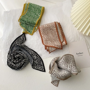 Close-up of pleated silk skinny scarves featuring geometric swirl patterns in various colors