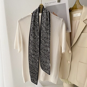 Detailed view of black and white geometric silk twilly scarf tied on a cream knit top