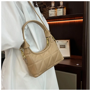 Close-up of beige quilted crossbody bag with golden hardware on vintage wood background