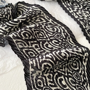 Macro detail of black and white pleated scarf with abstract geometric circle patterns