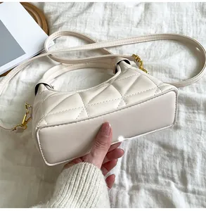 Detail of cream quilted PU leather handbag with gold buckle and textured finish