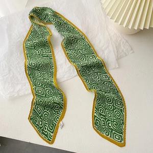 Close-up of pleated dark green silk scarf with golden geometric patterns and textures