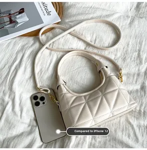 Compact quilted crossbody bag in beige shown next to a smartphone for size reference