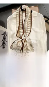 Detail of elegant beige silk twilly with black V-patterns tied on a white shirt collar